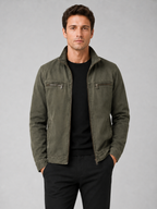 Man styling green washed cotton zip up jacket in a rugged travel and casual lifestyle outfit