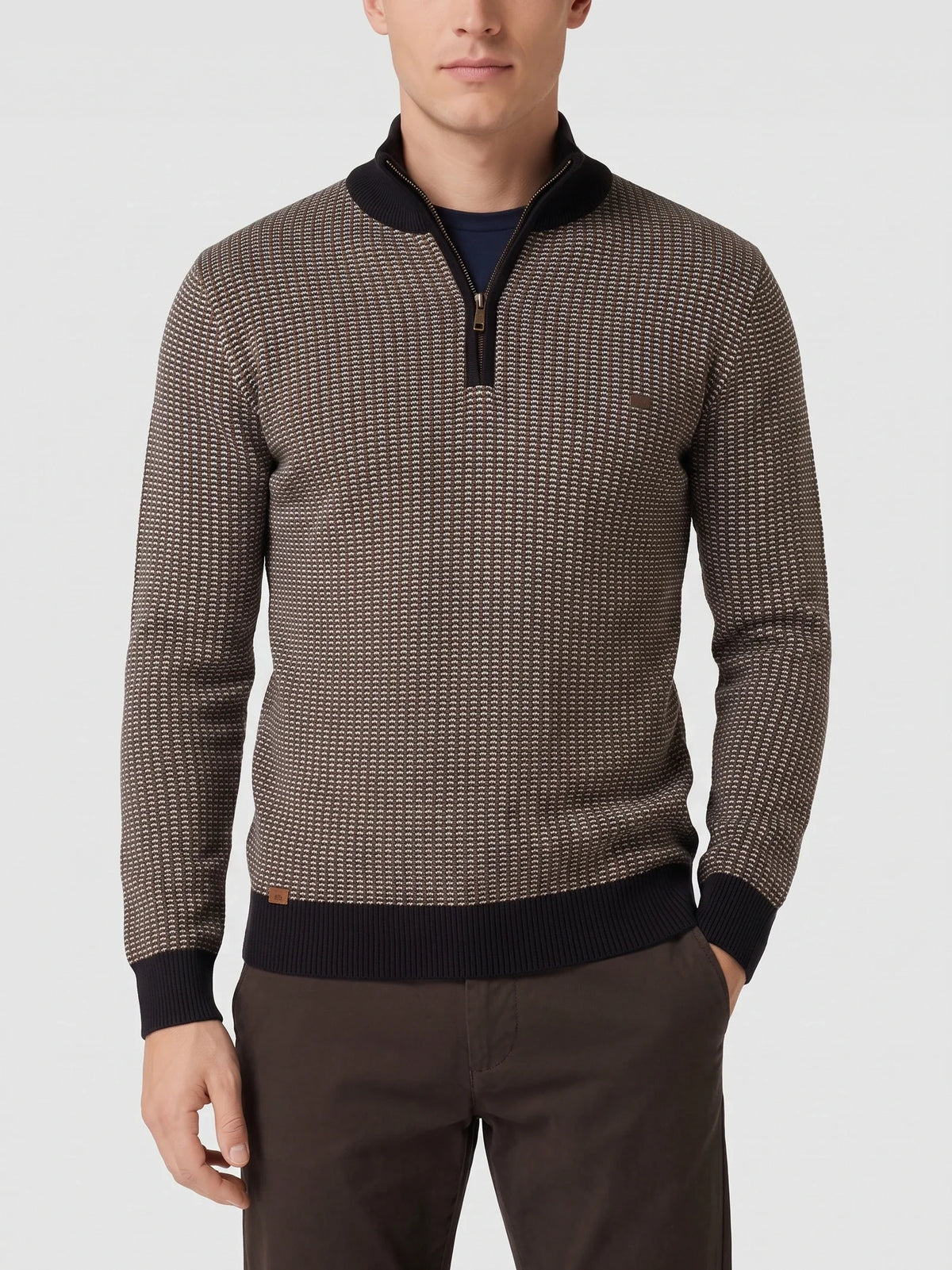 Man wearing a Brown knit quarter zip sweater on a sunlit patio beside a stone fireplace.