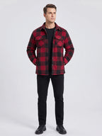 Man wearing a Red plaid flannel jacket with buttoned chest pockets while standing on a cabin porch among autumn leaves.